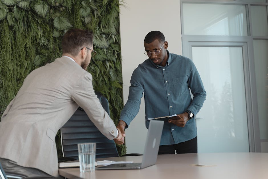 Two businessmen shaking hands in a modern office setting, sealing a business agreement.