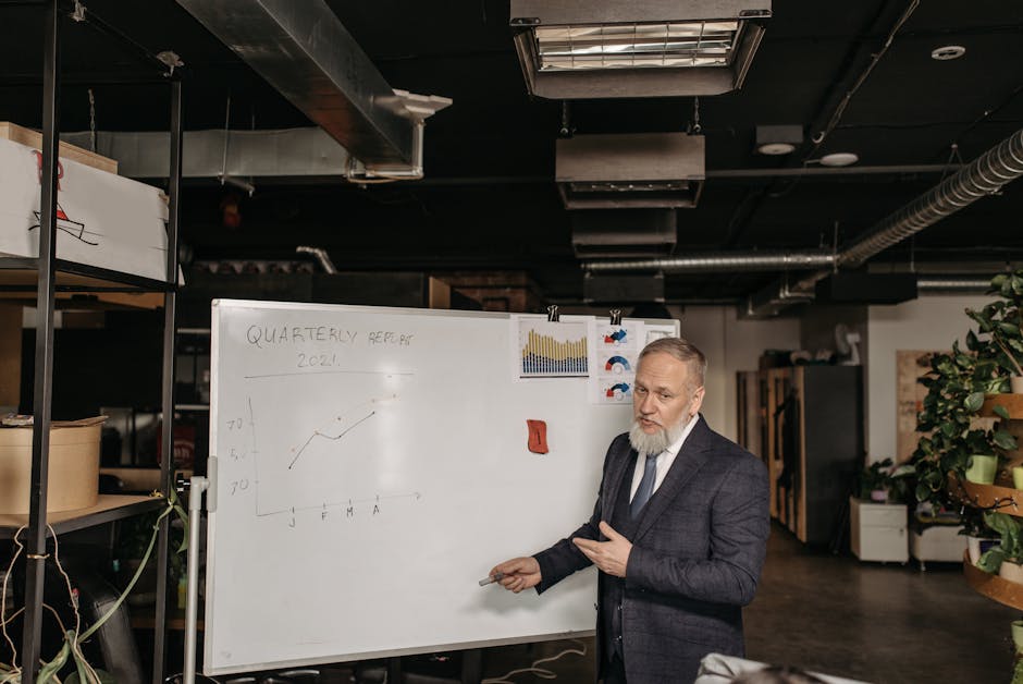 Businessman in suit presenting a quarterly report on a whiteboard in an office setting.